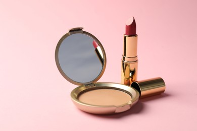 Photo of Open face powder with mirror and lipstick on pink background, closeup