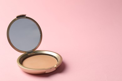 Photo of Open face powder with mirror on pink background, closeup. Space for text
