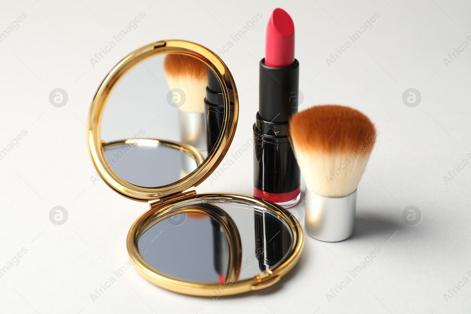 Open pocket mirror, brush and lipstick on light grey background, closeup Photo of Open pocket mirror, brush and lipstick on light grey background, closeup