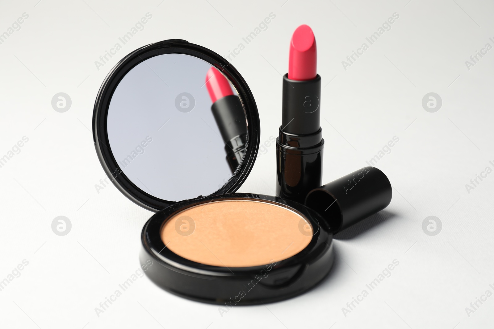 Open face powder with mirror and lipstick on light grey background, closeup Photo of Open face powder with mirror and lipstick on light grey background, closeup