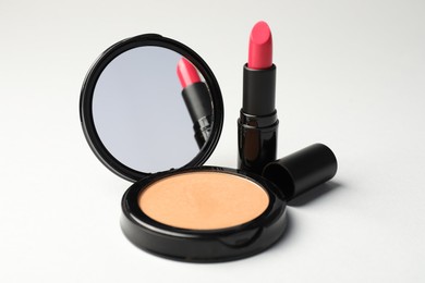 Photo of Open face powder with mirror and lipstick on light grey background, closeup