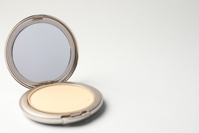 Photo of Open face powder with mirror on light grey background, closeup. Space for text