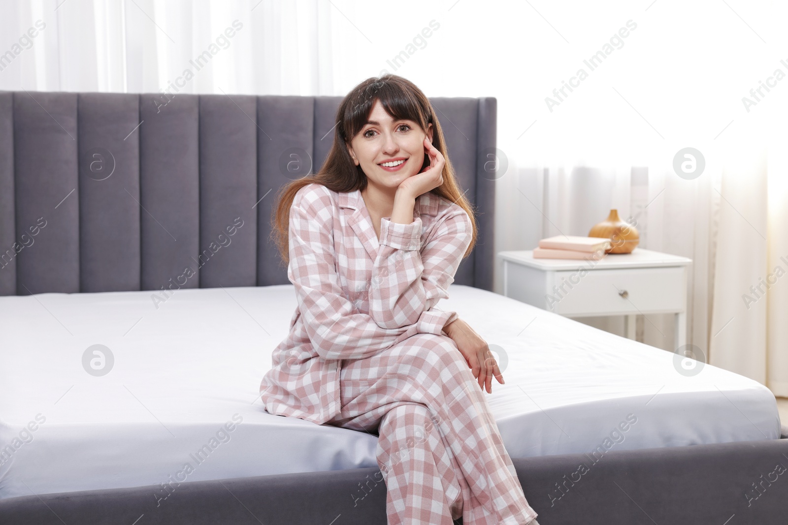 Photo of Beautiful woman sitting on soft mattress at home