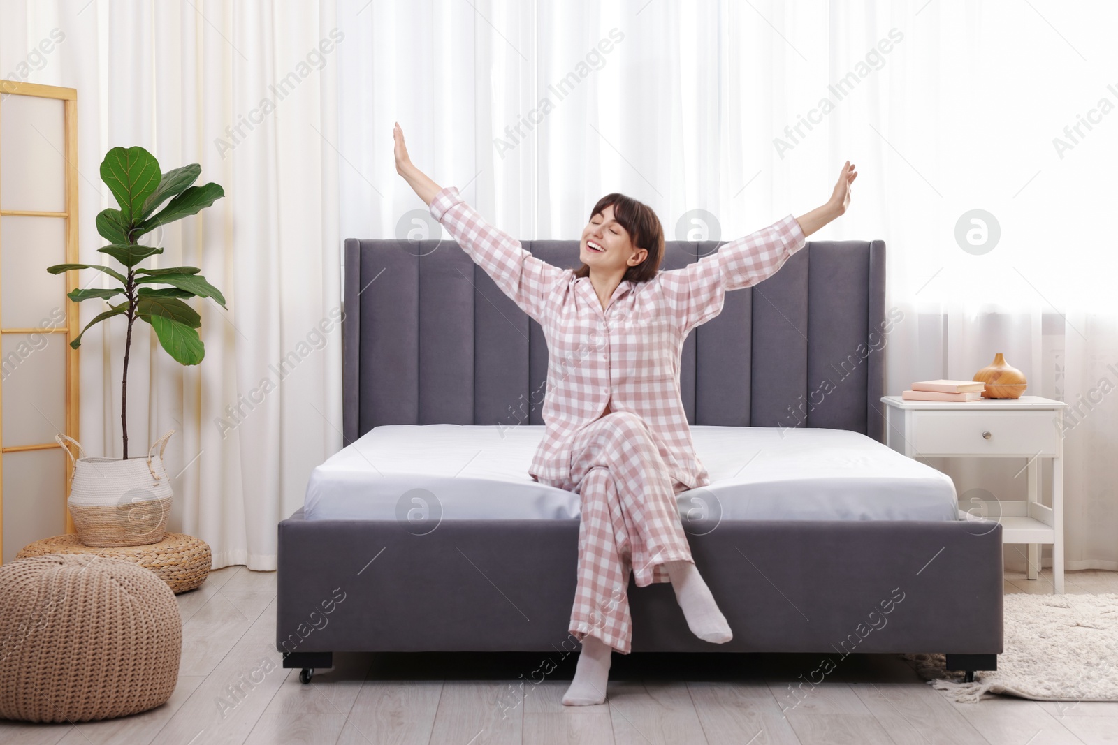 Photo of Beautiful woman sitting on soft mattress at home