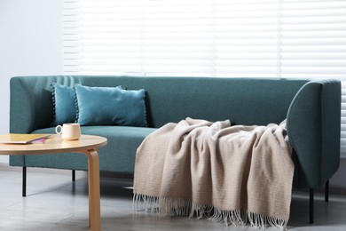 Photo of Woolen plaid on sofa and coffee table at home