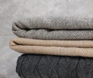 Photo of Folded woolen plaids against grey background, closeup