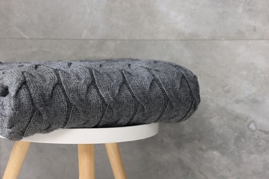 Photo of Folded woolen plaid on table near grey wall, closeup