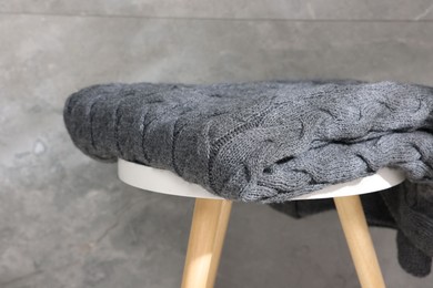 Photo of Folded woolen plaid on table near grey wall, closeup