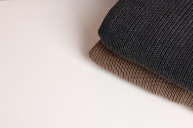 Photo of Stack of woolen sweaters on white background, top view. Space for text