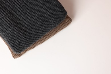 Photo of Stack of woolen sweaters on white background, top view. Space for text