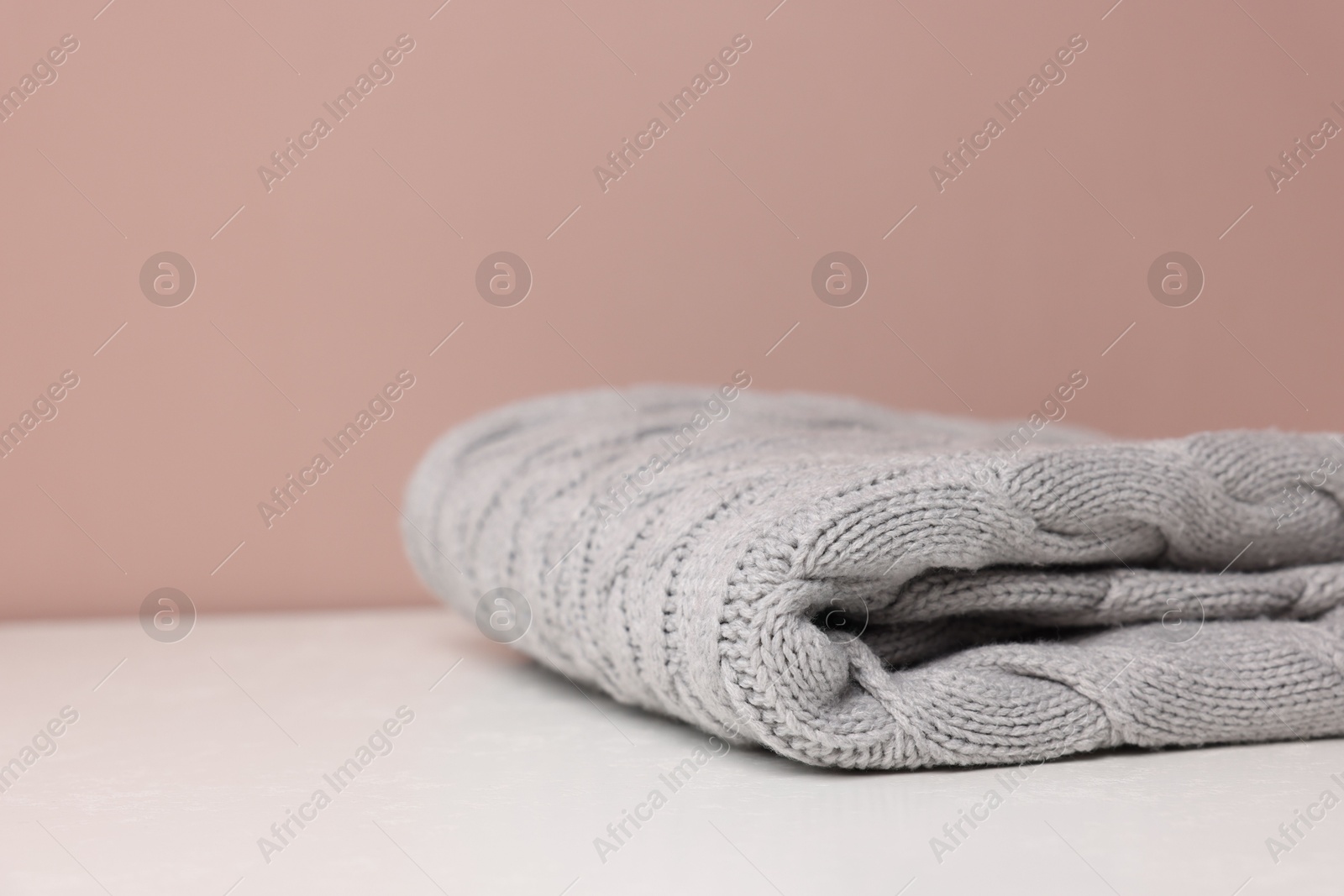 Folded woolen plaid on white table against color background, closeup. Space for text Photo of Folded woolen plaid on white table against color background, closeup. Space for text
