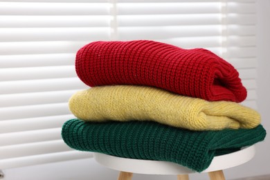 Photo of Stack of woolen sweaters on table near window, closeup
