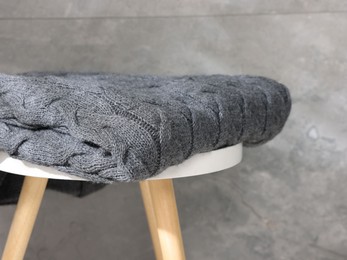 Photo of Folded woolen plaid on table near grey wall, closeup