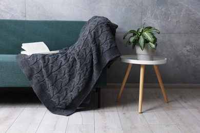 Photo of Woolen plaid and book on sofa at home