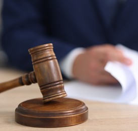 Photo of Judge working and gavel on desk indoors, selective focus