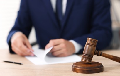 Photo of Judge working and gavel on desk indoors, selective focus