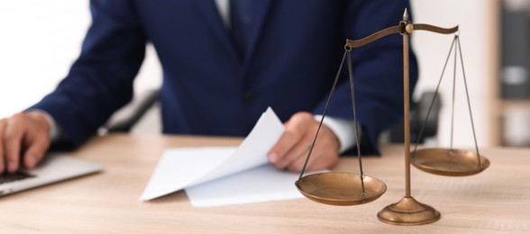 Photo of Judge working and scales on desk indoors, selective focus