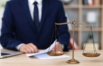 Photo of Judge working and scales on desk indoors, selective focus