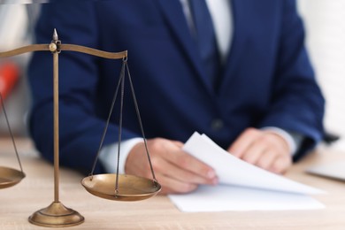 Photo of Judge working and scales on desk indoors, selective focus