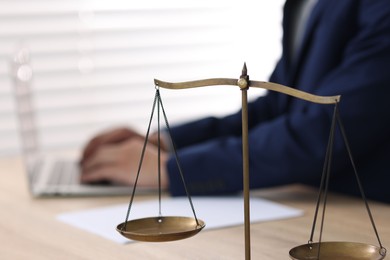 Photo of Judge working and scales on desk indoors, selective focus