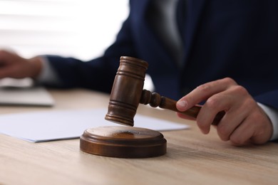 Photo of Judge with gavel working at desk indoors, closeup