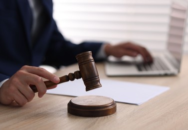 Photo of Judge with gavel working at desk indoors, closeup