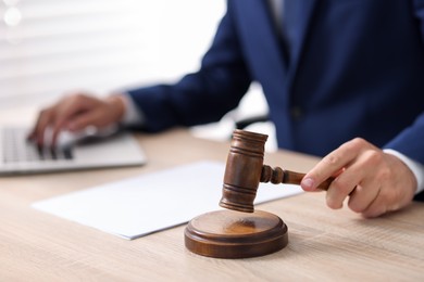 Photo of Judge with gavel working at desk indoors, closeup