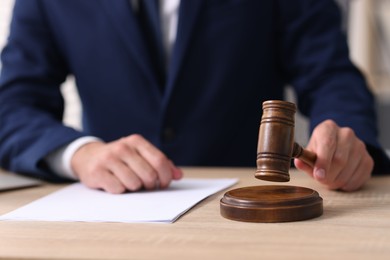 Photo of Judge with gavel working at desk indoors, closeup