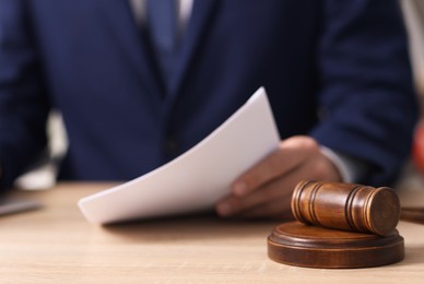 Photo of Judge working and gavel on desk indoors, selective focus