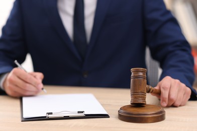Photo of Judge with gavel working at desk indoors, closeup