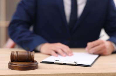 Photo of Judge working and gavel on desk indoors, selective focus