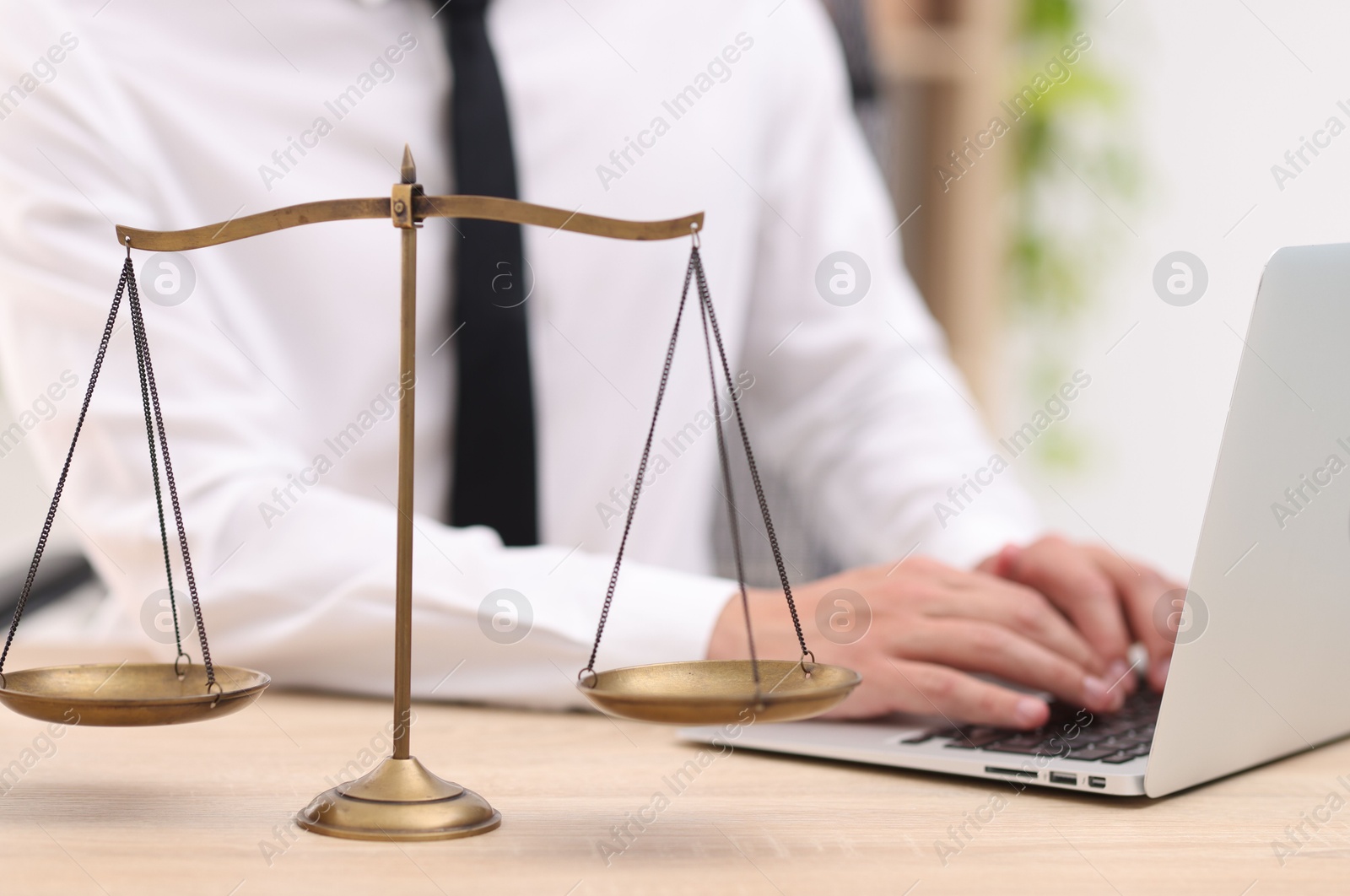 Judge working with laptop and scales on desk indoors, selective focus Photo of Judge working with laptop and scales on desk indoors, selective focus