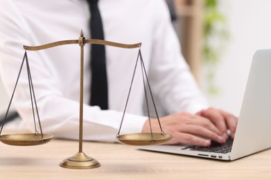 Photo of Judge working with laptop and scales on desk indoors, selective focus