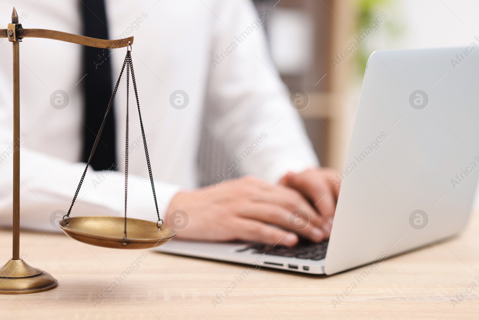 Judge working with laptop and scales on desk indoors, selective focus Photo of Judge working with laptop and scales on desk indoors, selective focus