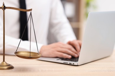 Photo of Judge working with laptop and scales on desk indoors, selective focus