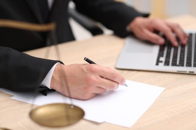 Photo of Judge working and scales on desk indoors, selective focus