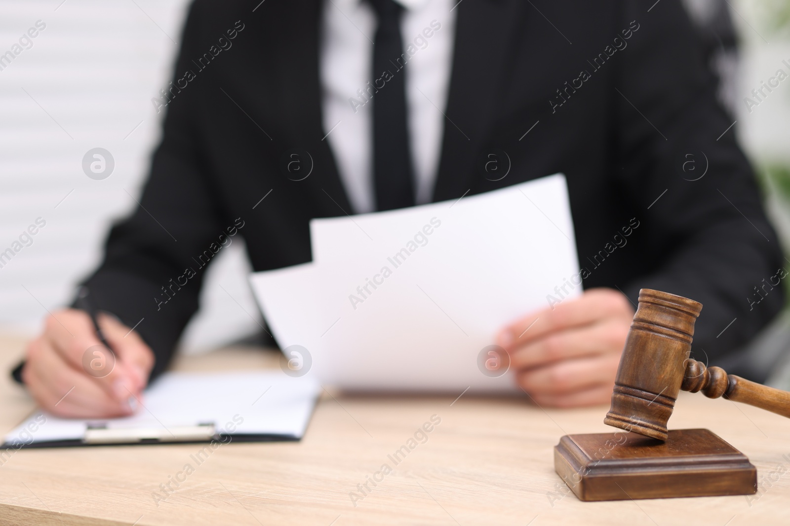 Photo of Judge working and gavel on desk indoors, selective focus