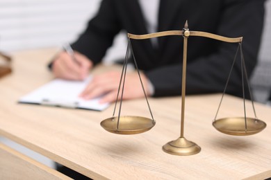 Photo of Judge working and scales on desk indoors, selective focus