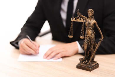 Photo of Judge working and Lady Justice figure on desk indoors, selective focus