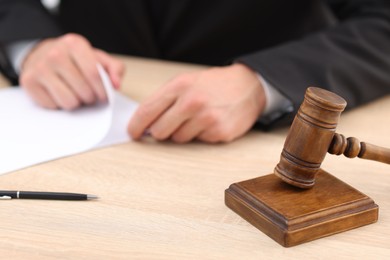Photo of Judge working and gavel on desk indoors, selective focus