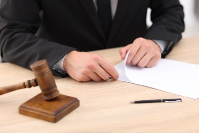 Photo of Judge working and gavel on desk indoors, selective focus