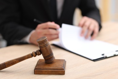 Photo of Judge working and gavel on desk indoors, selective focus