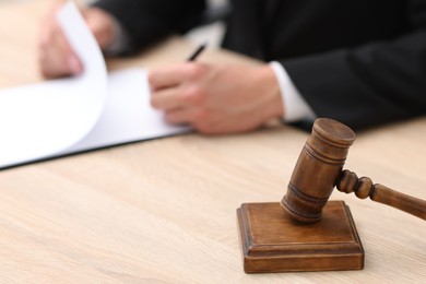 Photo of Judge working and gavel on desk indoors, selective focus