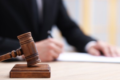 Photo of Judge working and gavel on desk indoors, selective focus