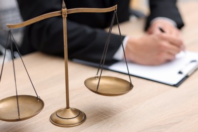 Photo of Judge working and scales on desk indoors, selective focus