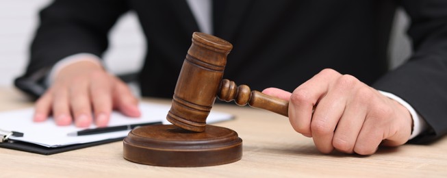 Photo of Judge with gavel working at desk indoors, closeup