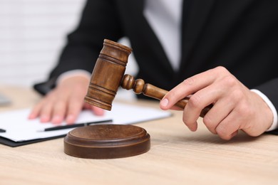 Photo of Judge with gavel working at desk indoors, closeup