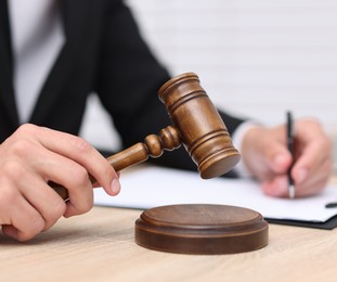 Photo of Judge with gavel working at desk indoors, closeup