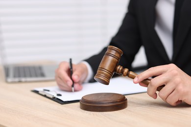 Photo of Judge with gavel working at desk indoors, closeup