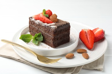 Photo of Piece of delicious chocolate cake with strawberries, almonds and mint on white table, closeup